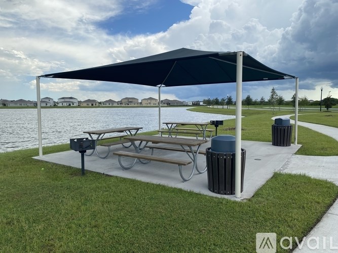 A picnic area with a canopy and benches is set up near a body of water.