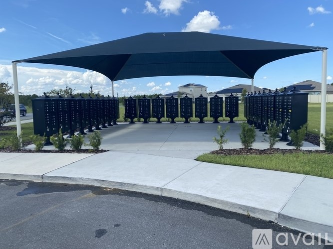 A large black shade structure is over a parking lot.