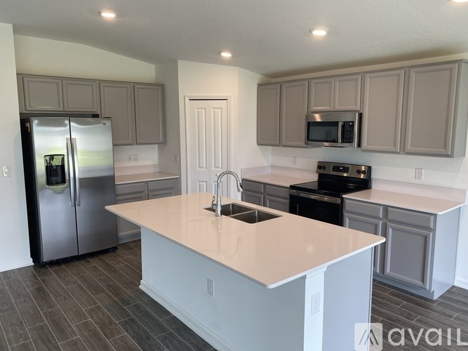 A kitchen with a refrigerator, sink, and microwave.