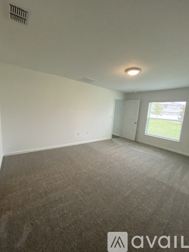 A room with a carpeted floor and a window showing daylight outside.