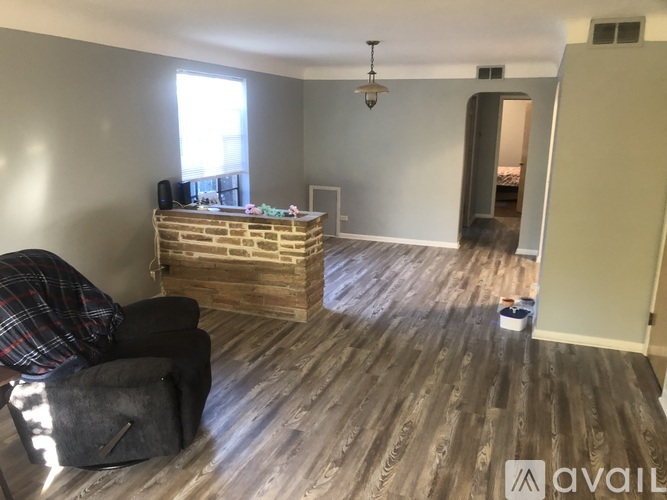 A room with wooden flooring and a brick wall fireplace.