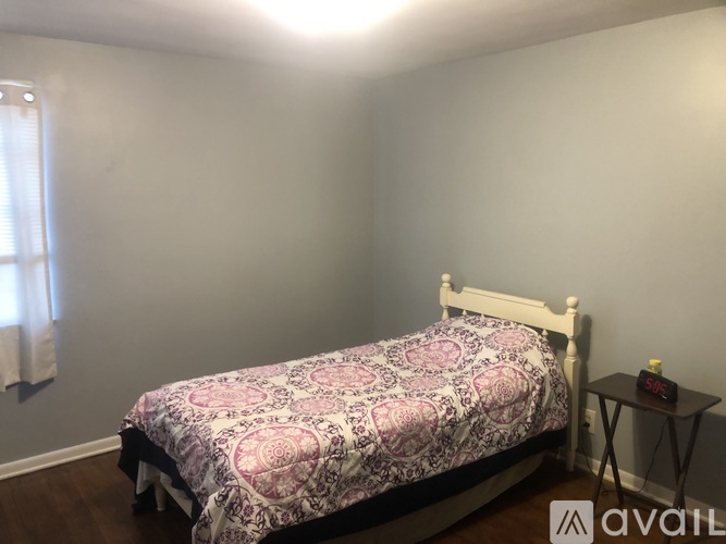 A bedroom with a bed, nightstand, and window.