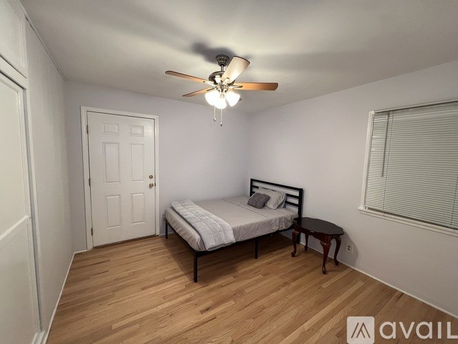 A bedroom with a bed, a ceiling fan, and a small table.