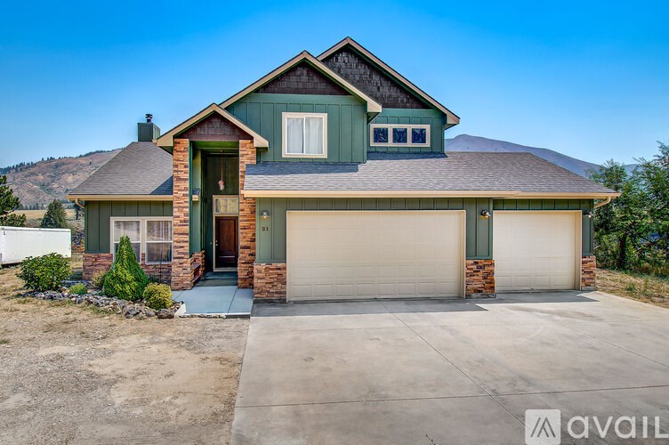 A house with a brown roof and a green garage door is for sale.