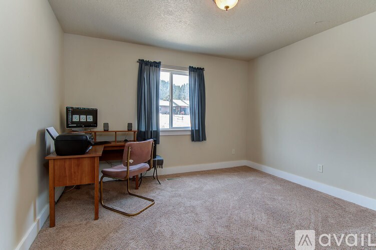A room with a carpeted floor, a wooden chair, and a small table with a radio on it.