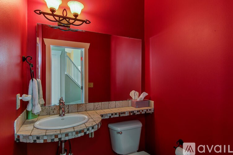 A bathroom with red walls and a checkered counter.