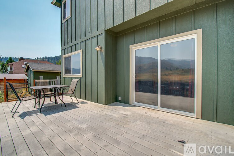 A patio with a table and chairs is on the deck of a house.