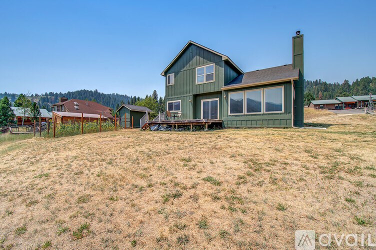 A house with a green exterior is surrounded by a grassy field.