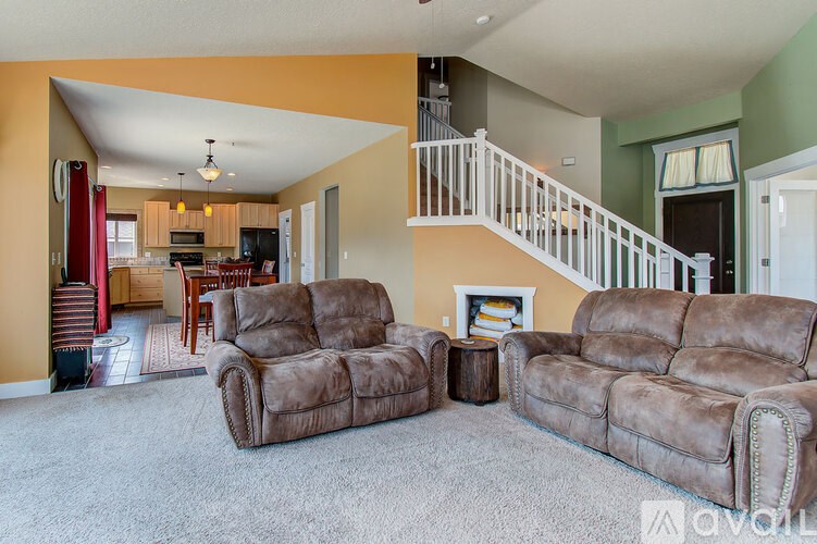 A living room with two brown couches and a fireplace.