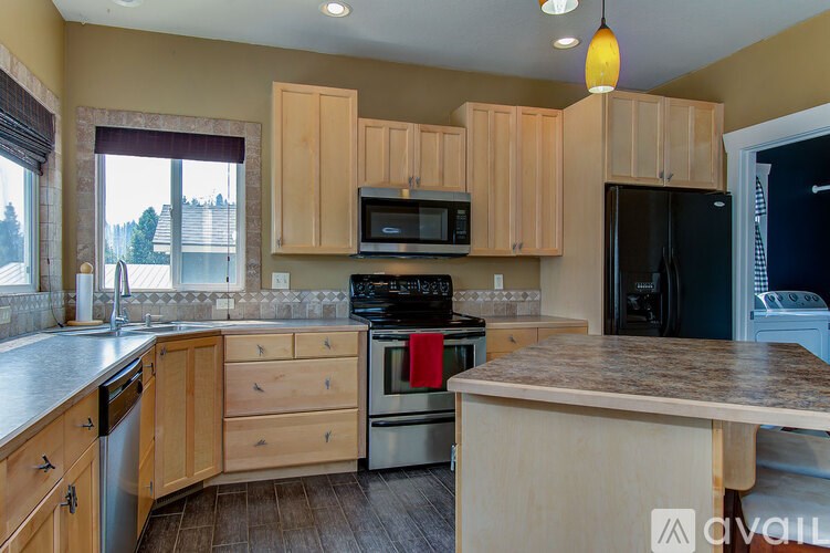 A kitchen with wooden cabinets and a black refrigerator.