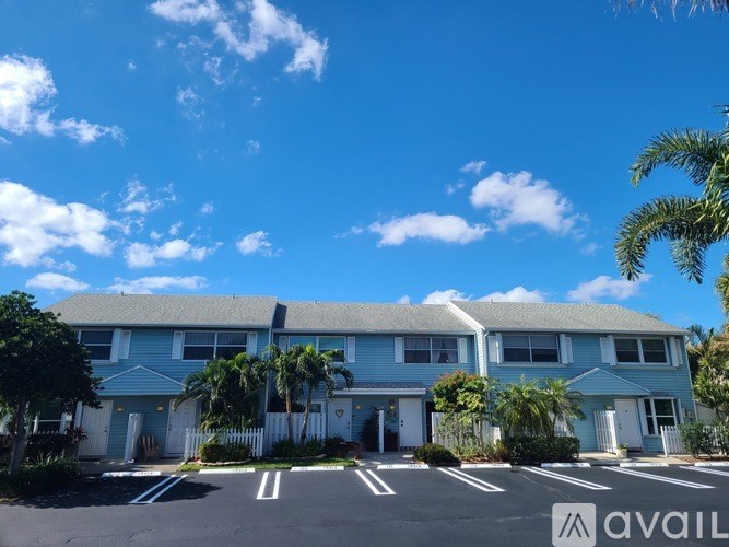 A blue house with a white fence and a white sign that says "AVAIL" in front of it.
