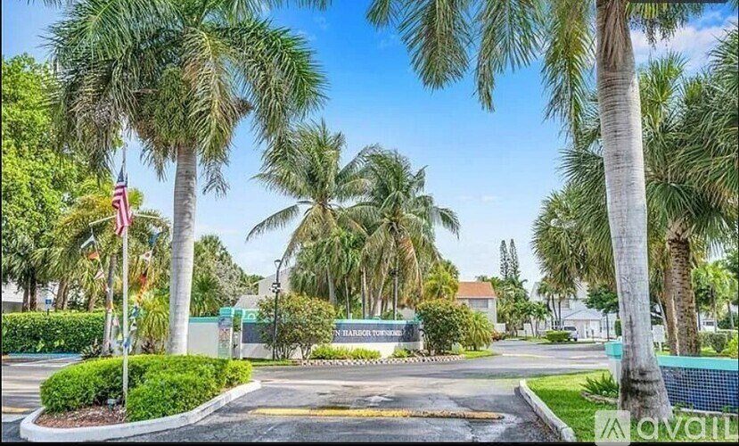 A sunny day at the entrance of a building with palm trees and flags.