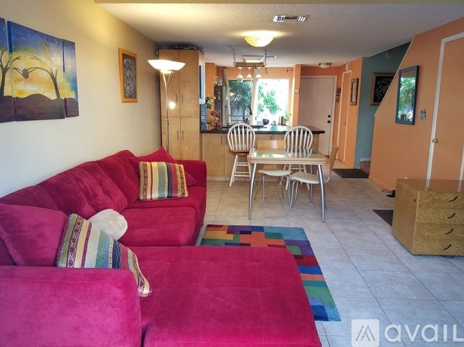 A living room with a red couch and a painting on the wall.