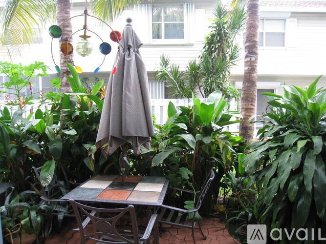 A patio with a table, chairs, and a grey umbrella.