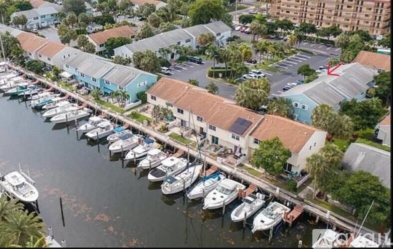 A marina with boats docked in the water and buildings in the background.