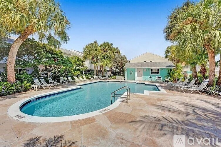 A pool surrounded by palm trees and lounge chairs.