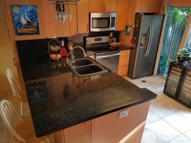 A kitchen with a black counter top and a refrigerator.