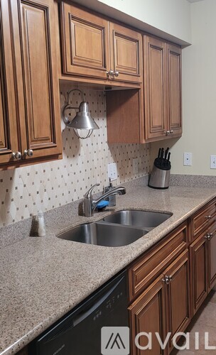 A kitchen with brown cabinets and a black dishwasher.