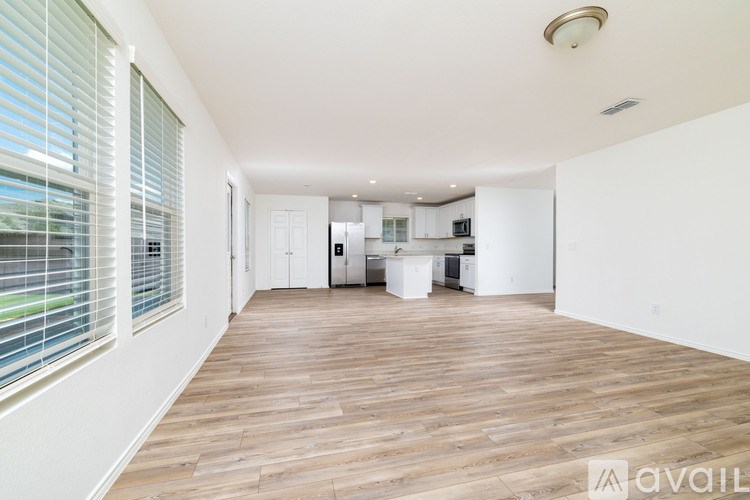 A spacious room with wooden flooring and white walls.