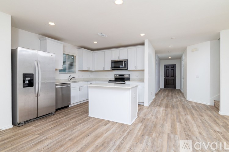 A kitchen with white cabinets and a wooden floor.