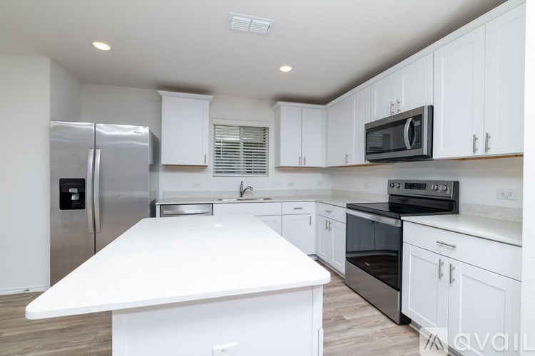 A kitchen with white cabinets and a white island.