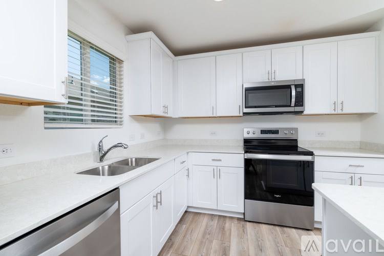 A kitchen with white cabinets and a stainless steel sink.