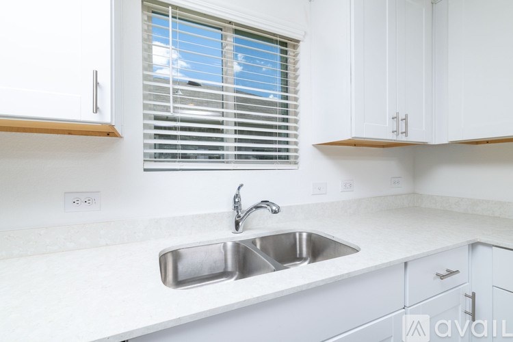 A kitchen with a white sink and cabinets.
