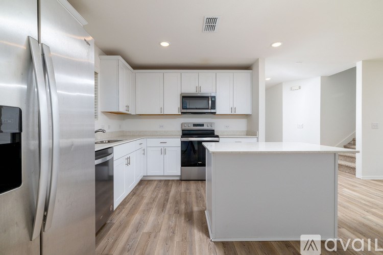 A modern kitchen with a stainless steel refrigerator and white cabinets.
