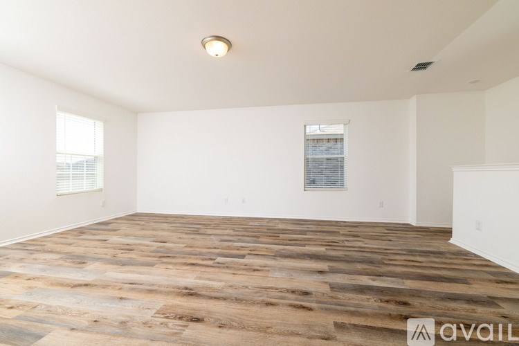 A room with wooden flooring and a window with blinds.