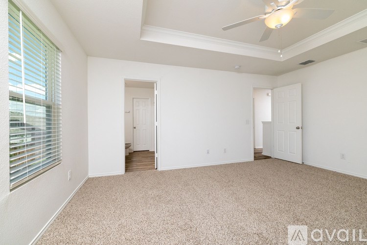 A room with a carpeted floor and a ceiling fan.