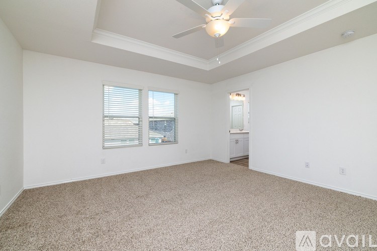A spacious room with a ceiling fan and carpeted floor.