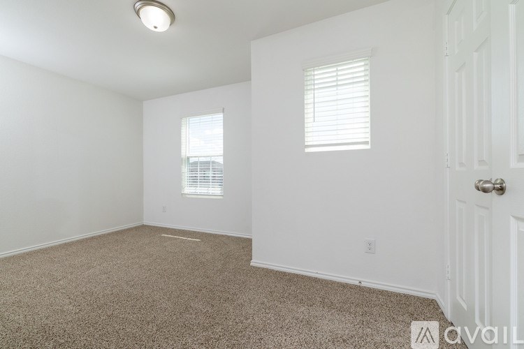 A carpeted room with a door and a window.