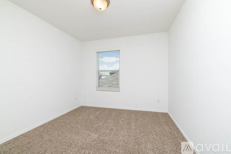 A room with a carpeted floor and a window with blinds.