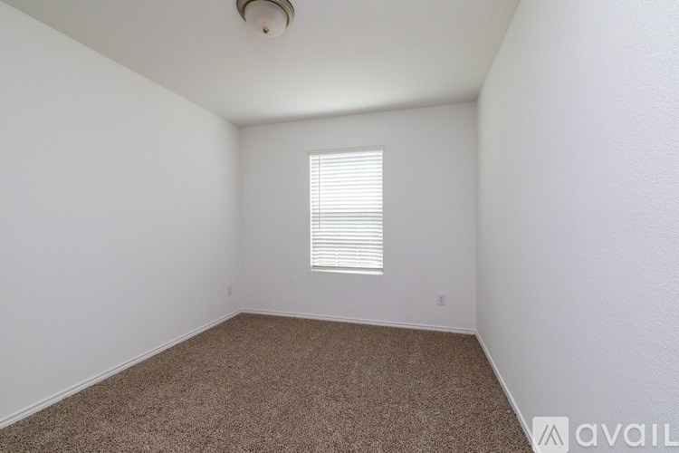 A room with a carpeted floor and a window with blinds.
