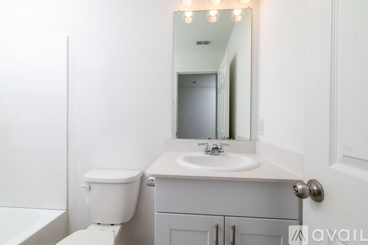 A white bathroom with a toilet, sink, and mirror.