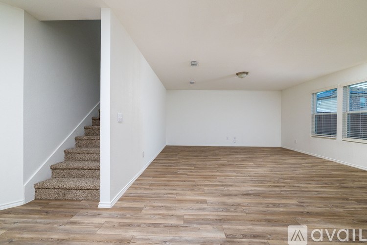 A room with wooden flooring and a staircase leading to another room.