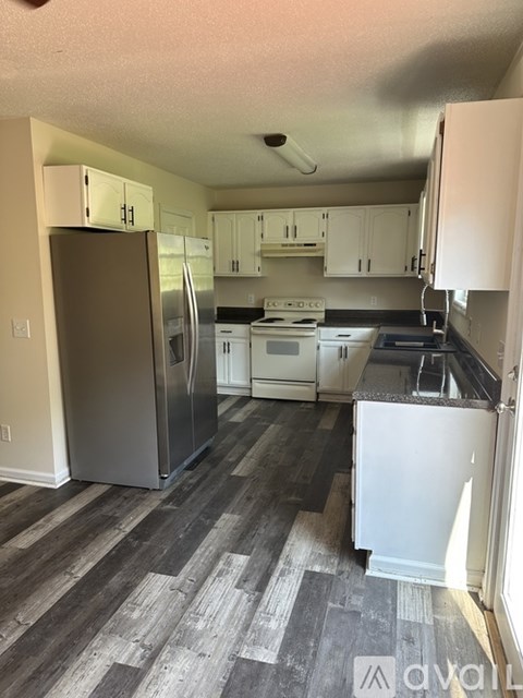 A kitchen with a refrigerator, stove, and cabinets.
