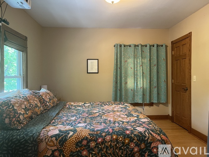 A bedroom with two beds and a window with curtains.
