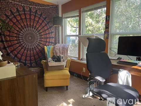 A room with a desk, chair, and a window with a view of trees.