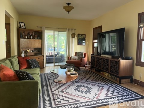 A living room with a green couch and a patterned rug.
