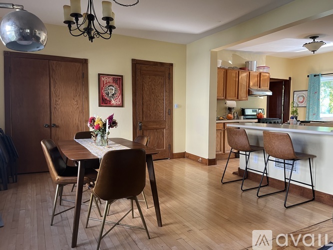 A kitchen with a table and chairs in the foreground and a dining area in the background.
