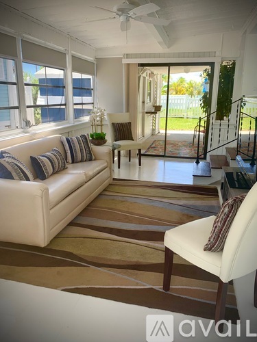 A living room with a white couch and a striped rug.