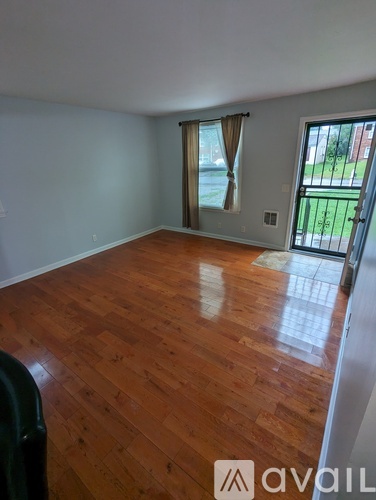 A room with wooden flooring and a sliding glass door leading to a backyard.