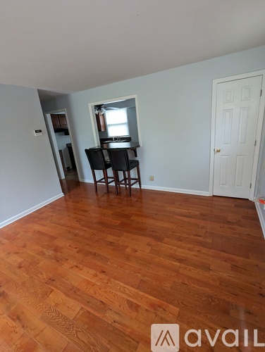 A room with wooden flooring and a dining table with chairs.