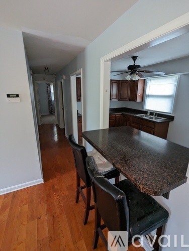 A kitchen with a table and chairs in the foreground and a hallway in the background.
