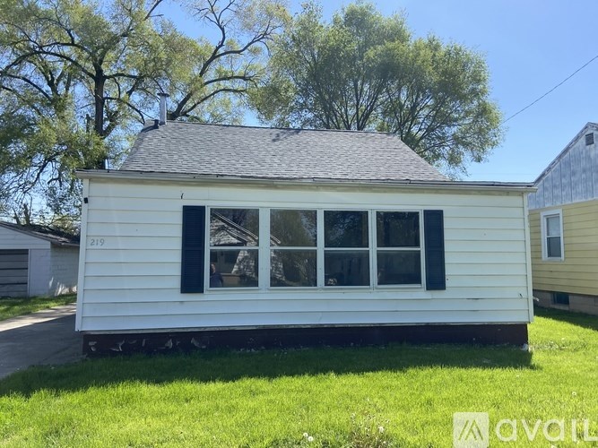 A small white house with black shutters is for sale.