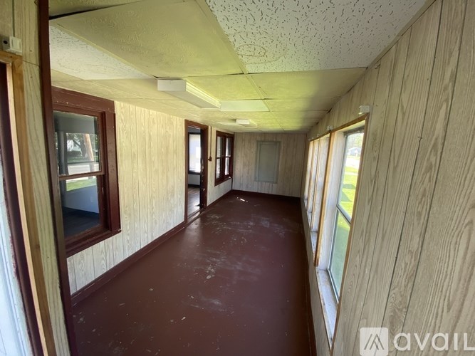 A long hallway with wooden walls and brown flooring.