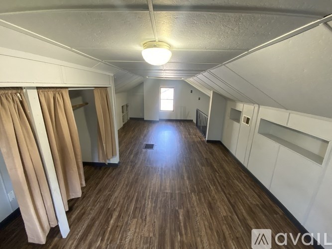 A long, narrow room with wooden floors and white walls.