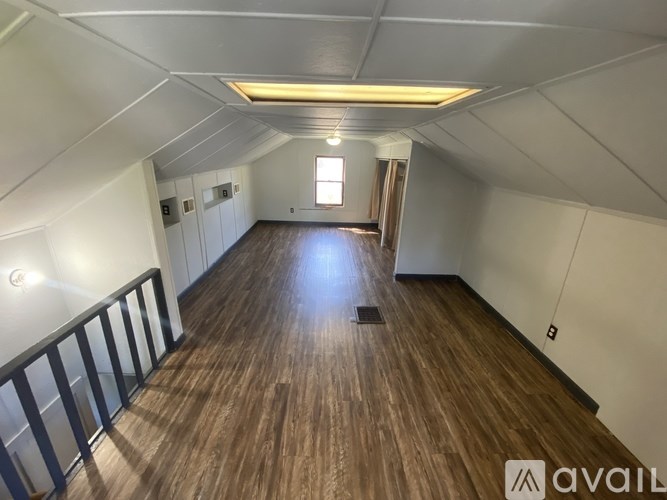 A spacious attic room with wooden flooring and a skylight.