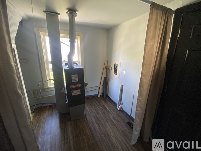 A room with a wood floor, a window, and a radiator.